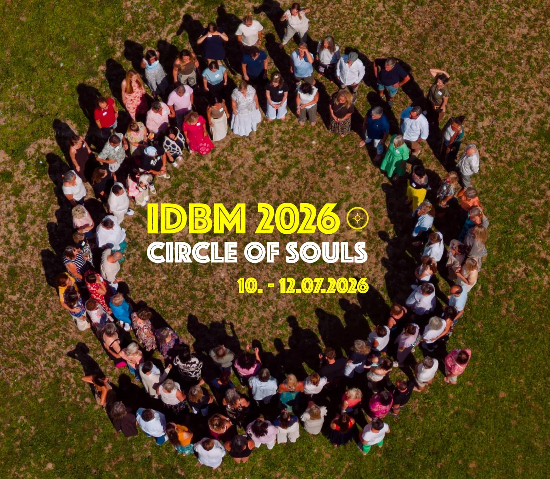 Teilnehmende des IDBM Circle of Souls 2026 bilden auf einer Wiese einen Kreis, aufgenommen aus der Vogelperspektive.